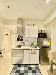 a white kitchen with a sink and a refrigerator at 1 Bedroom Unit with Massage Chair, Karaoke, Smart TV at Azure Urban Resort in Manila