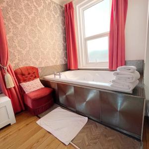 a bathroom with a tub with a window and a red chair at G Boutique Hotel in Portsmouth