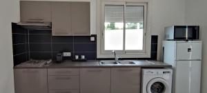 a kitchen with a sink and a white refrigerator at Le Pavillon Les BUISSONNETS in Salon-de-Provence