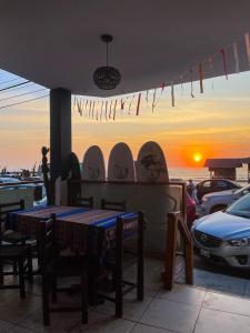 - une table et des chaises sur une terrasse avec vue sur le coucher du soleil dans l'établissement Totora Surf Hostel, à Huanchaco