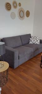 um sofá cinzento numa sala de estar com piso em madeira em L'Escapade Appartement T1 douillet tout confort em Roanne
