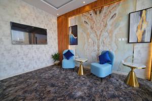 una sala de espera con 2 sillas azules y TV en فندق زوايا الماسية(العوالي) en Medina