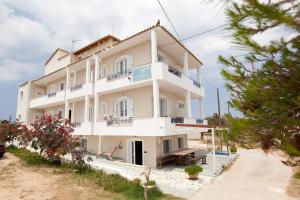 エラフォニソスにあるKontogoni Roomsの青いバルコニー付きの白い大きな建物