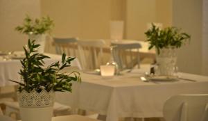 a table with white table cloth and green plants on it at Ino Village Hotel in Samos