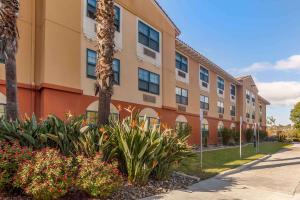 an apartment building with a palm tree and flowers at Extended Stay America Suites - San Diego - Hotel Circle in San Diego