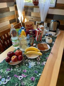 una mesa con manzanas, naranjas, plátanos y otros alimentos para el desayuno en Wypoczynek Hnatczak en Debrzno