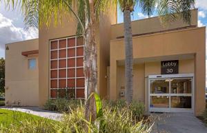 ein Gebäude mit Palmen davor in der Unterkunft Extended Stay America Suites - Orange County - Irvine Spectrum in Irvine