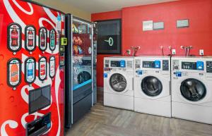 a laundry room with three washing machines and a soda machine at Extended Stay America Suites - Orange County - Irvine Spectrum in Irvine