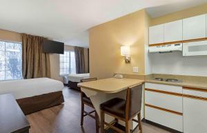 a hotel room with a bed and a kitchen with a desk at Extended Stay America Select Suites - St Louis - Airport - Central in Bridgeton