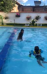 two people swimming in a swimming pool at Hotel Cocli in Roldanillo