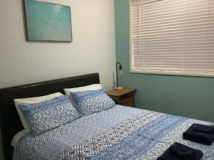 Torquay Beach Holiday Home في Torquay: غرفة نوم مع سرير ووسائد زرقاء ونافذة