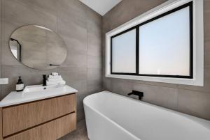 un bagno con vasca, lavandino e specchio di Kira Lani - Pet friendly Tura a Tura Beach Altre 34 foto