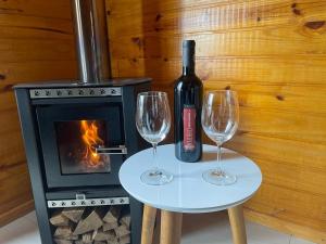 uma garrafa de vinho e dois copos de vinho numa mesa com um fogão em Pousada Recanto das Cachoeiras em Urubici