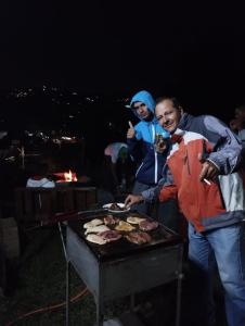a group of people cooking food on a grill at El paso Gh #1 in Guarne