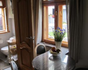 a table with a bowl of fruit and a vase of flowers at Smilčių namelis in Palanga