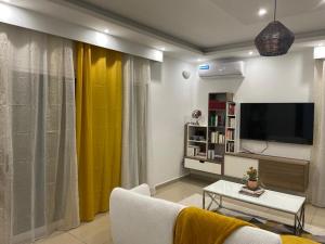 a living room with a tv and a yellow curtain at Le Lointain in Mtsamboro