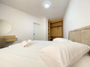 ein Schlafzimmer mit einem großen weißen Bett mit Handtüchern darauf in der Unterkunft LIV Apartments in Vlorë