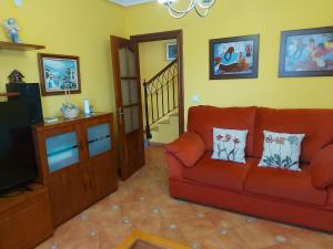 ein Wohnzimmer mit einem roten Sofa und einem TV in der Unterkunft Villa Mercedes in Luarca