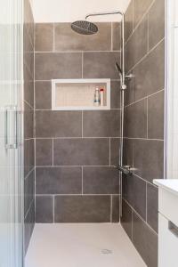 uma casa de banho com um chuveiro com azulejos cinzentos em Cozy Haven Retreat em Lisboa