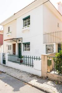 een wit huis met groene deuren en een hek bij Cozy Haven Retreat in Lissabon