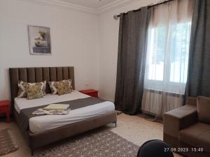 ein Schlafzimmer mit einem Bett, einem Stuhl und einem Fenster in der Unterkunft Fufa Apartment in Monastir