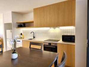 cocina con mesa y fregadero en U Suites on Trieste Way, en Paraparaumu