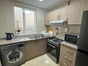 a kitchen with a stove and a sink and a window at شقة البحيره in Sharjah