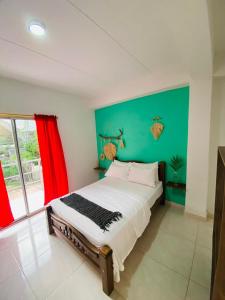 um quarto com uma cama grande e uma parede verde em Casa Guiwa Hostel em Palomino
