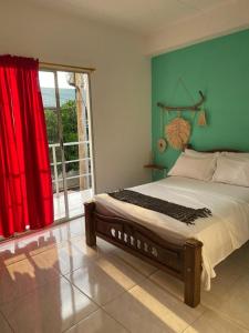 um quarto com uma cama grande e uma cortina vermelha em Casa Guiwa Hostel em Palomino