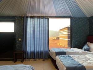 a bedroom with two beds and a large window at Beyond Wadi Rum Camp in Wadi Rum