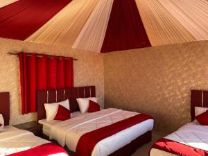 a bedroom with two beds with red curtains at Beyond Wadi Rum Camp in Wadi Rum