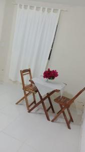 uma mesa e duas cadeiras e um vaso de flores em Casa Siulan em Porto de Galinhas