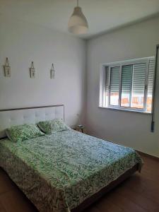 a bedroom with a bed with a green comforter and a window at Blue Sardine Hostel in Portimão