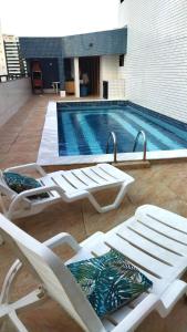 una piscina con tumbonas blancas y una piscina en Charming 1-BR Apartment in Boa Viagem - with Ocean View, en Recife