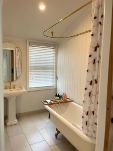 een witte badkamer met een bad en een wastafel bij Little Roper Cottage in Mount Beauty