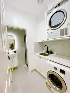 uma lavandaria branca com um lavatório e uma máquina de lavar roupa em The Daisy House - Family-friendly & top convenient location em Melbourne
