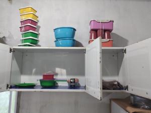 a cupboard with bowls and other dishes in it at Casa laranja cabuçu in Saubara
