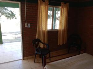 a bedroom with a bed and two chairs and a window at Los nidos 3 in Villa Cura Brochero