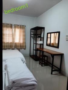 a bedroom with a bed and a desk and a mirror at Rutcha homestay Betong รัชชา โฮมสเตย์ เบตง in Betong