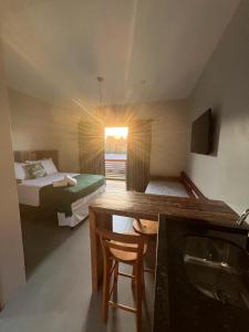 a room with two beds and a desk and a sink at Pousada Vielas do Rosa - centrinho da praia do rosa in Praia do Rosa