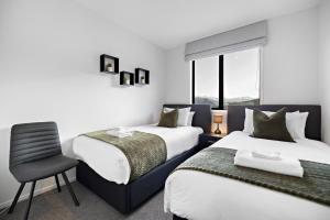 um quarto de hotel com duas camas e uma cadeira em Remarkable Mountain Scene - A Modern Escape em Frankton