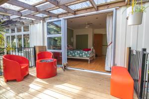 a screened porch with red chairs and a bedroom at Waimoana Garden Accommodation in Whangarei