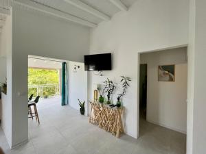 a white living room with a tv on the wall at Les Villas du Bambou - Villa Bambou jusqu'à 6 pers in Le Gosier