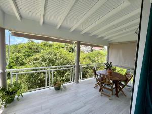 patio con mesa y sillas en el balcón en VILLA BAMBOU Domaine à l'ombre du Bambou jusqu'à 6 pers, Parc national de la Guadeloupe, en Le Gosier