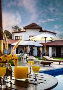 a table with glasses of orange juice on a table near a pool at Finca Las Margaritas in Chicoana