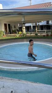 Ein kleiner Junge, der im Pool sitzt. in der Unterkunft Mactan Oasis- Stylish Condo with Pool and Netflix in Agus