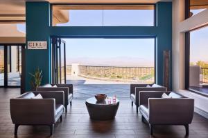 eine Lobby mit Stühlen, einem Tisch und großen Fenstern in der Unterkunft ADERO Scottsdale Resort, Autograph Collection in Scottsdale