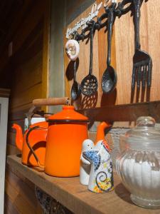 un hervidor de té naranja y utensilios de cocina en un estante en Refúgio Amor Demasiado en São Francisco de Paula
