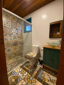 a bathroom with a toilet and a tile wall at Refúgio Amor Demasiado in São Francisco de Paula