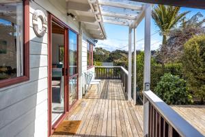 un porche de una casa con terraza de madera en Onetangi Beach Retreat - Waiheke Holiday Home, en Onetangi